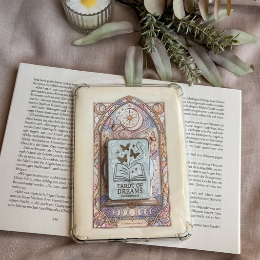 Divined Chapter Set: E-Reader Insert in transparenter Hülle mit dem passenden Grip auf einem aufgeschlagenen Buch