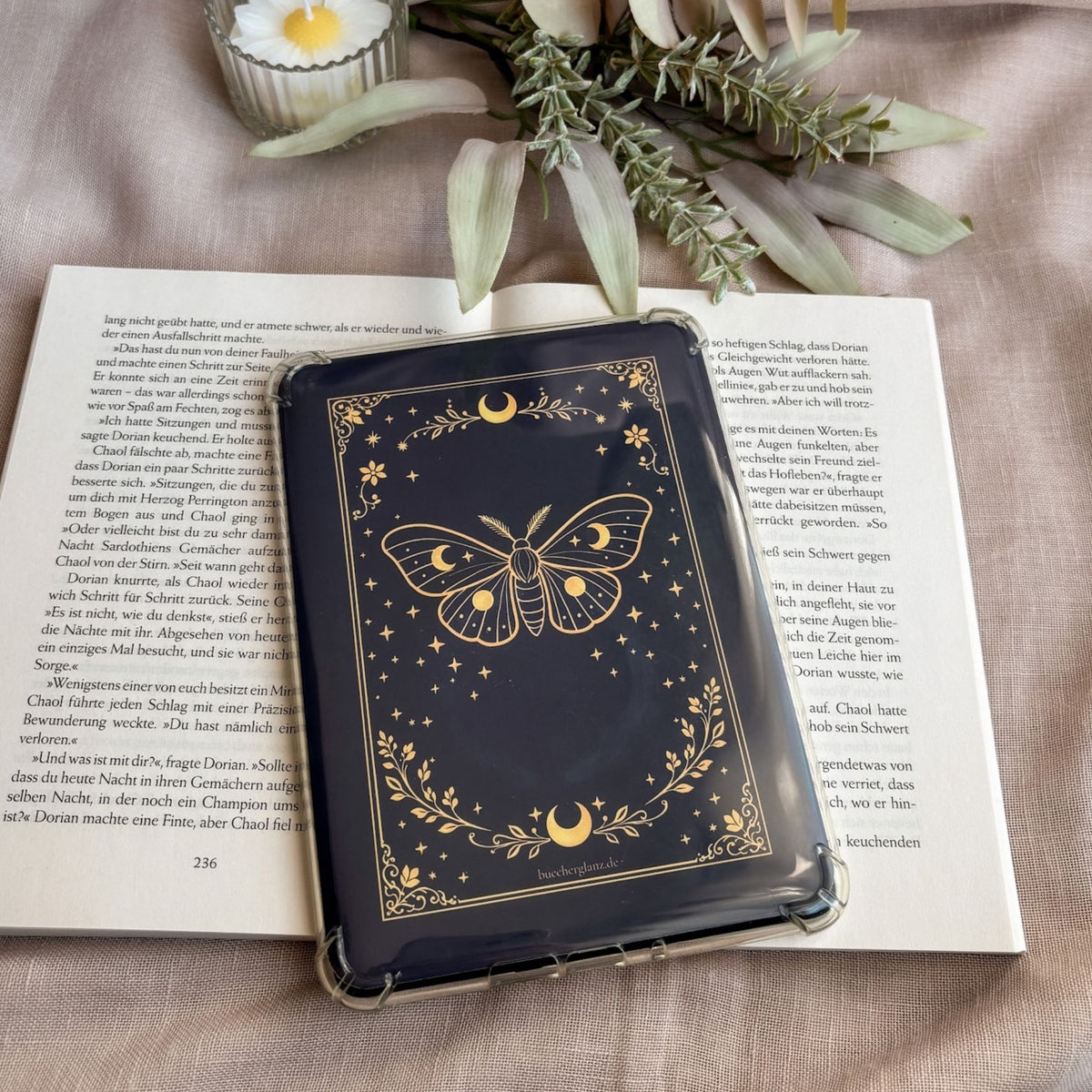 Enchanted Moth E-Reader Insert in transparenter Hülle auf einem aufgeschlagenen Buch