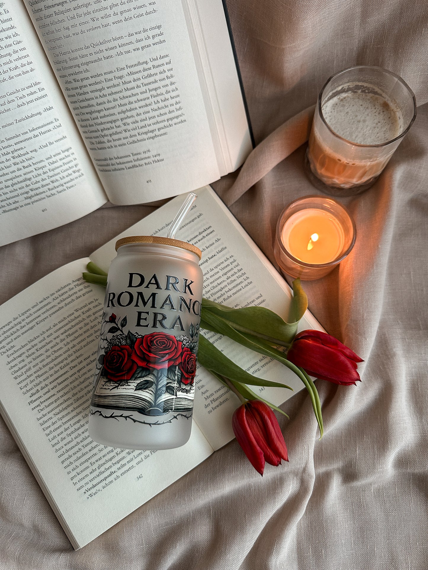 Dark Romance Era Glastumbler auf Buch mit Kerze und roten Tulpen – Dark Romance Reading Setup buecherglanz