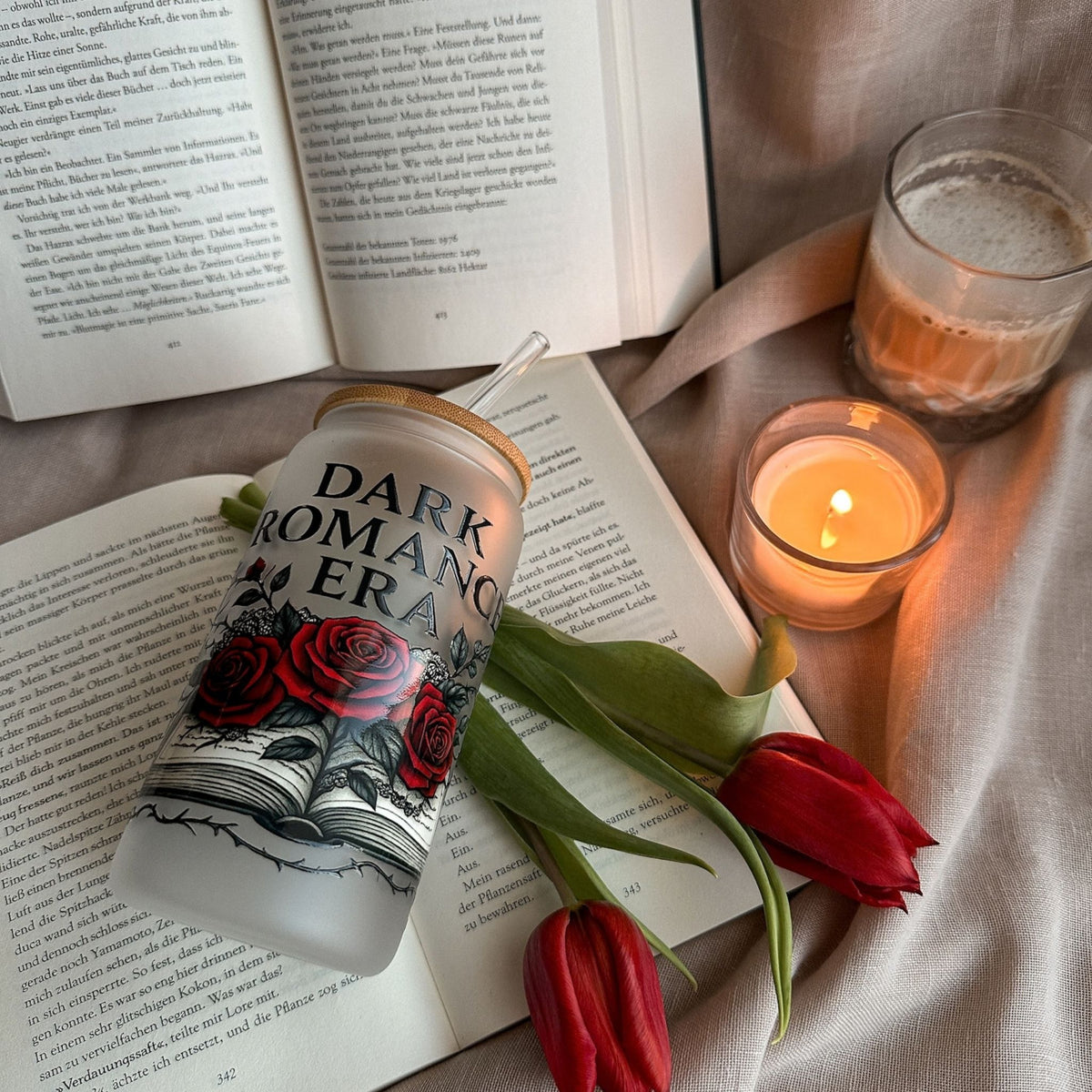 Frosted 16-oz-Glastumbler „Dark Romance Era“ mit roten Rosen und Buchmotiv zwischen offenen Büchern, Kerze und roten Tulpen