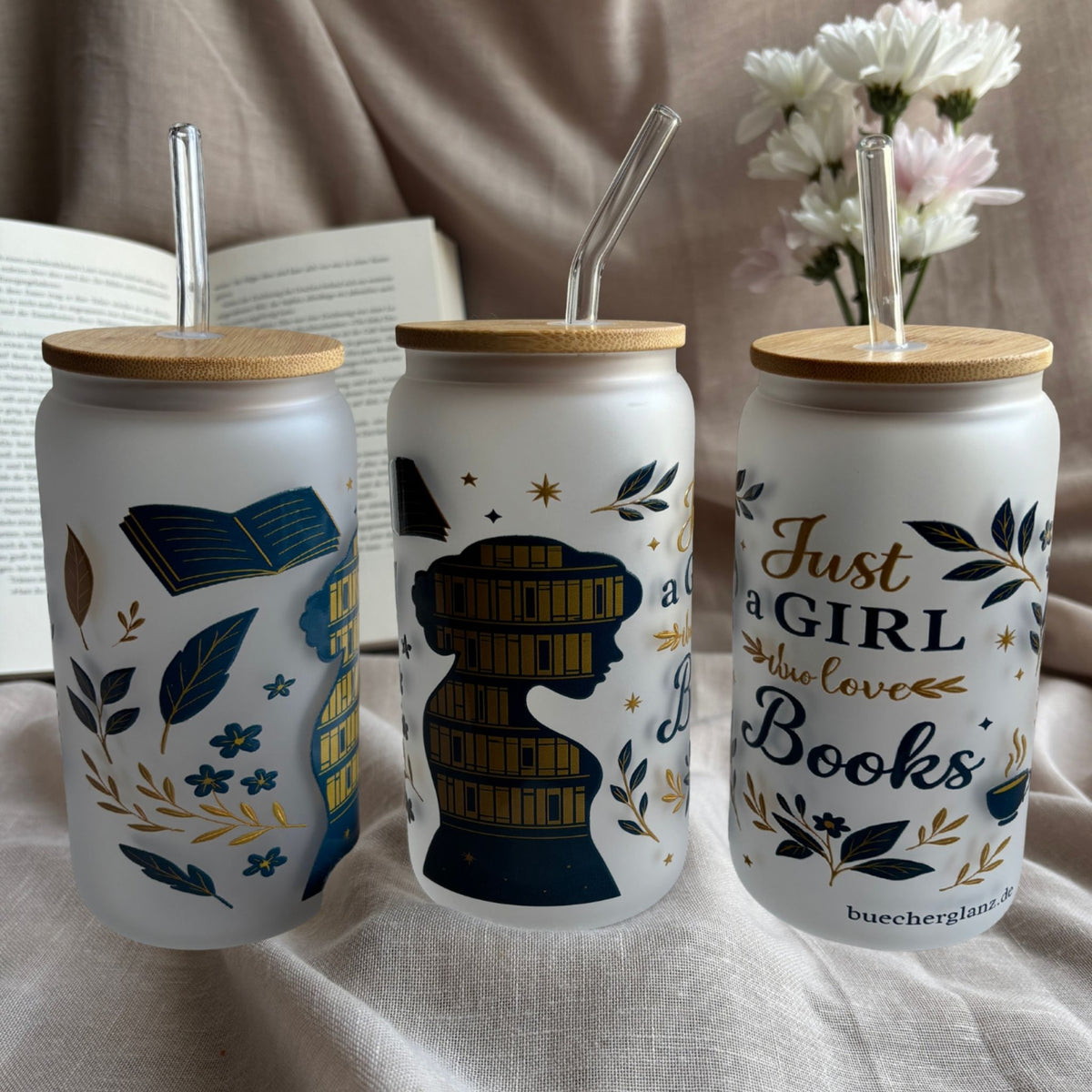 Frosted 16 oz glass tumbler “Just a Girl Who Loves Books” with bookshelf silhouette next to an open book and white flowers