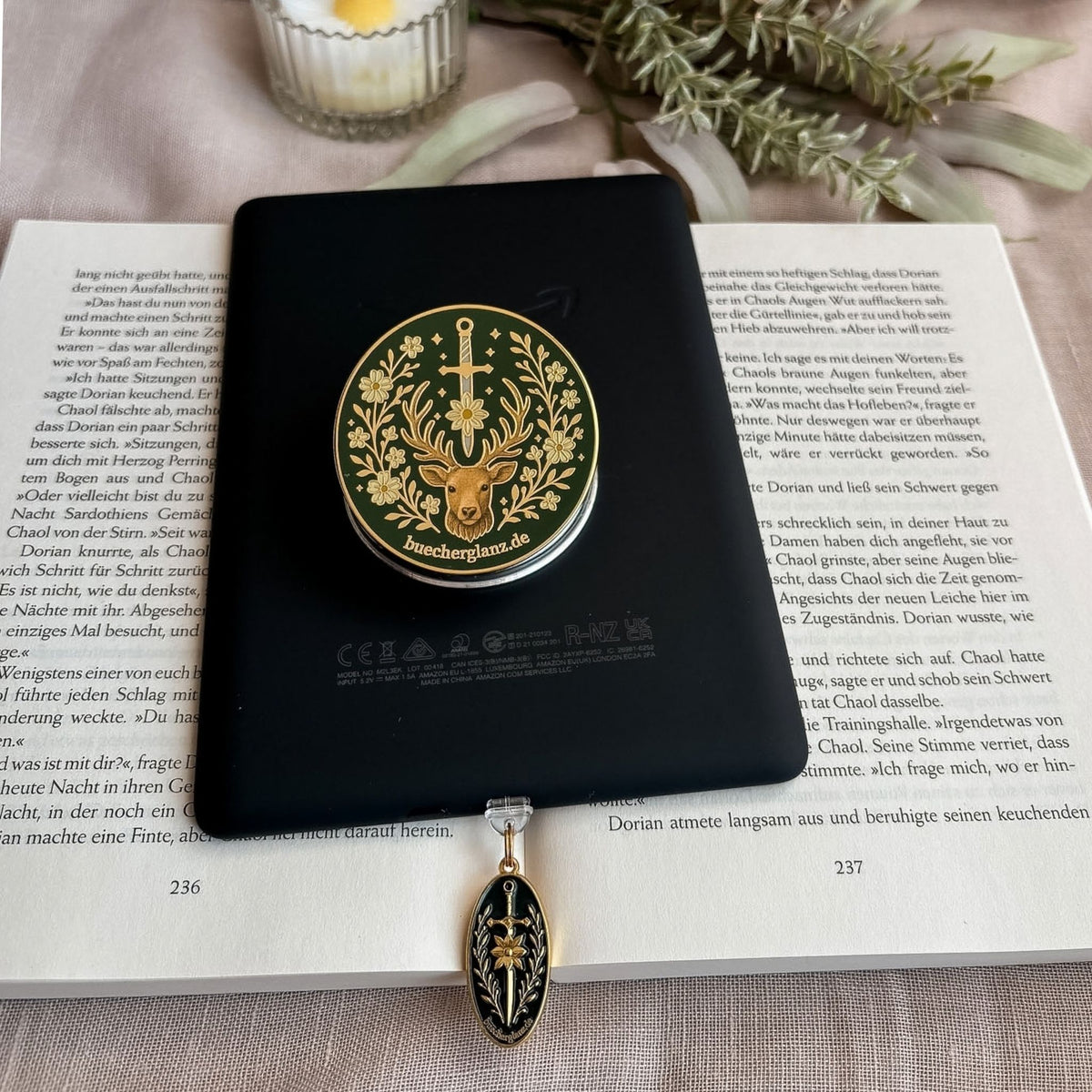 E-Reader Grip Heir of the Forest in Gold auf einem schwarzen E-Reader, unten der Charm Plug Blade & Bloom