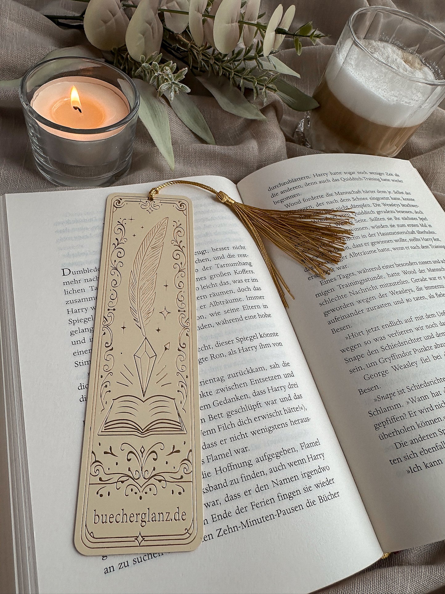 The Inksworn – Metall-Lesezeichen – Lifestyle liegend im Buch Goldquaste Kerze Warm Cozy, buecherglanz