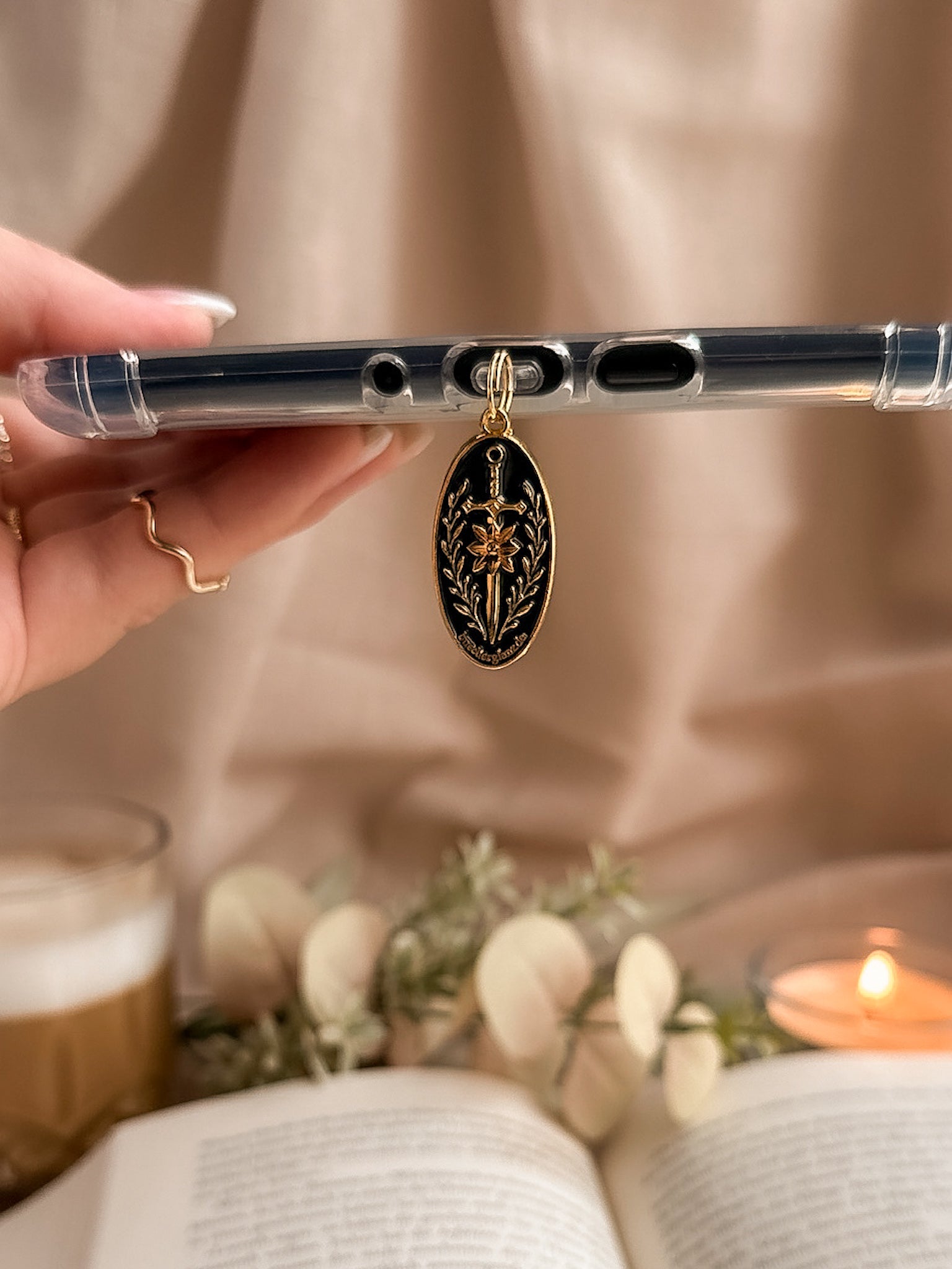 Blade & Bloom – USB-C Dustplug – Lifestyle hängend am Kindle Hand Kerze weiße Blumen, buecherglanz